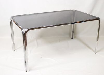 une table en verre avec des pieds chromés sur fond blanc