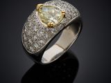 a yellow diamond and diamond ring on a black surface