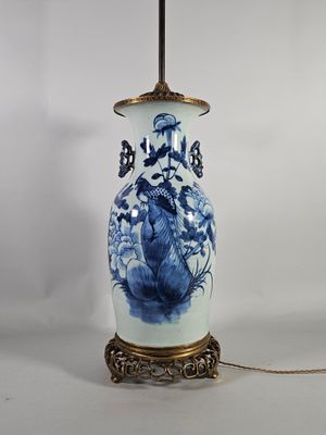 un vase bleu et blanc posé sur un socle muni d'une chaîne