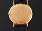 a close up of a gold plated wrist watch on a black leather strap