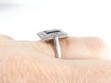 a woman ' s hand holding a ring with a blue stone