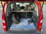 the back of a red van with its trunk open and a tire in the back
