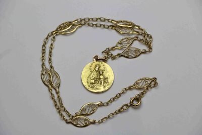 Gros plan sur un collier en or sur lequel se trouve une pièce de monnaie
