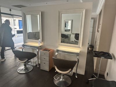 une photo d'un salon de coiffure avec des fauteuils et des miroirs