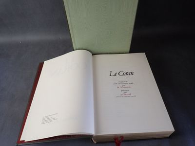 un livre ouvert posé sur une table, à côté d'une boîte verte