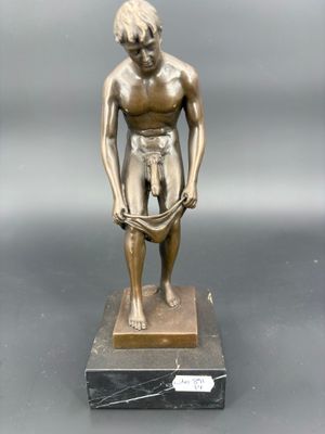 statue en bronze représentant un homme les mains dans les poches, posée sur un socle en marbre