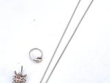 a close up of a necklace, ring, and earring on a white surface