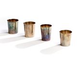 four metal cups are lined up in a row on a white surface