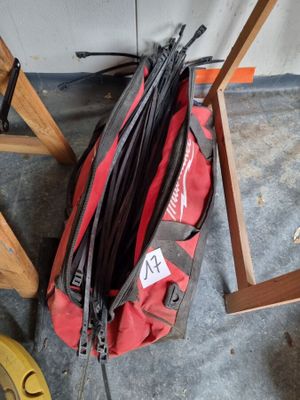 un sac de voyage rouge posé par terre à côté d'une paire de ciseaux