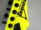a close up of a yellow electric guitar with a black neck