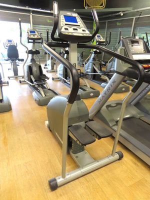 row of stationary exercise bikes in a gym with a television in the background