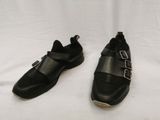 une paire de chaussures en cuir noir ornées de boucles, posées sur une surface blanche