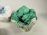 two pieces of green and blue crystals on a white surface