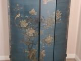 a blue cabinet with flowers and birds painted on it