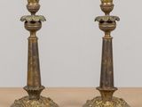 une paire de bougeoirs anciens en laiton posés sur une table en bois