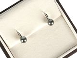 une paire de boucles d'oreilles en perles noires, présentée dans un coffret cadeau sur fond blanc