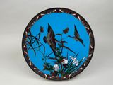 a blue plate with birds and flowers painted on it