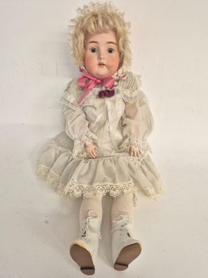 an old doll with blonde hair and a white dress sitting on a white surface