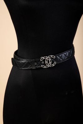 a woman wearing a black dress and a black belt with a silver buckle