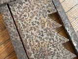 a large metal object on a wooden floor next to a piece of wood