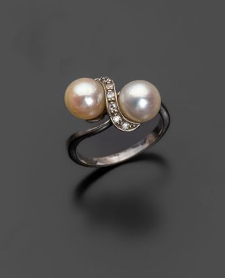 une bague en perles blanches et diamants sur une surface noire