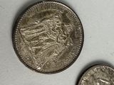 three silver coins sitting on top of a white surface next to each other