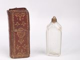 a small glass bottle next to a book on a white surface