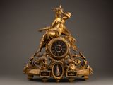 a gold clock with a statue on top of it