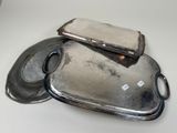 two silver trays on a white table with a silver lid