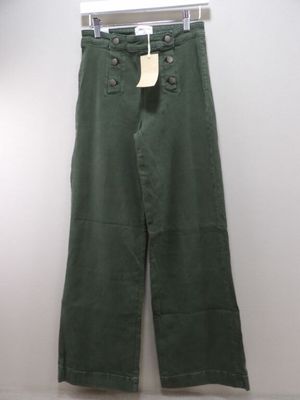 green pants hanging on a hanger against a white wall