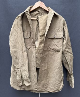 an old jacket hanging on a hanger against a blue wall