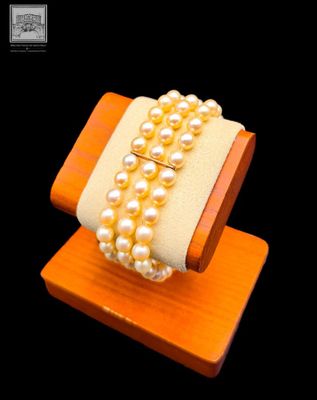 un bracelet orné de perles, posé sur un support en bois, sur fond noir