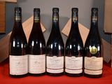 six bouteilles de vin sont alignées sur une table rouge