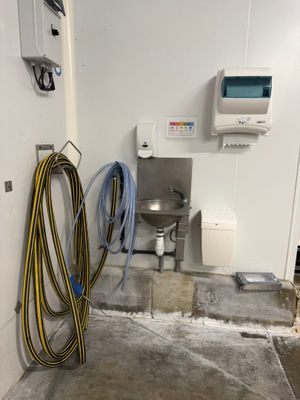 une pièce équipée d'un lavabo et d'un tuyau d'arrosage posé à même le sol