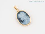a close up of a gold pendant with a blue and white cameo