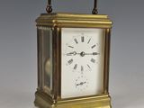 une petite horloge en laiton avec des chiffres romains sur le cadran