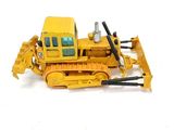 un bulldozer miniature posé sur une surface blanche