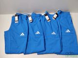 quatre paires de pantalons de survêtement Adidas bleus posés sur une table blanche