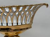 a gold and silver bowl on a stand on a table
