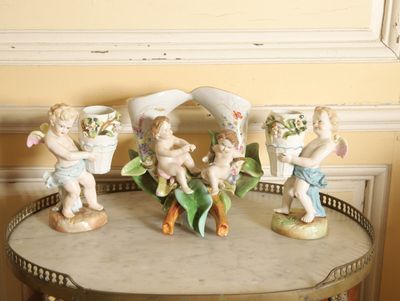 quatre figurines posées sur une table sur laquelle se trouve un vase