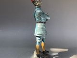 a figurine of a man in a blue uniform stands on a white surface