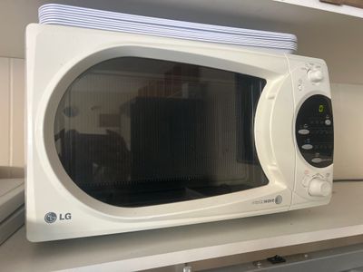 a white microwave sitting on a shelf in a kitchen