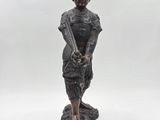 bronze statue of a woman holding a baseball bat on a rock