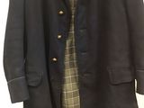 a black coat with a plaid dress underneath it