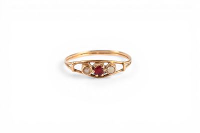 un gros plan d'une bague en or sertie d'une pierre rouge et blanche