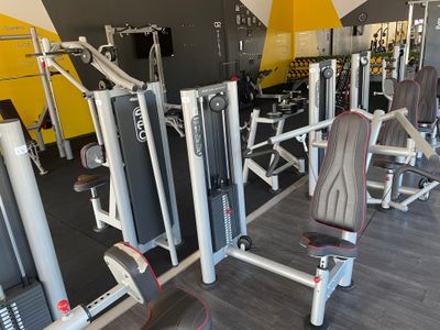 de nombreux appareils de musculation avec un mur jaune en arrière-plan