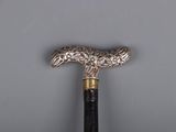 an old silver and black cane with a handle on a gray surface
