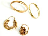 trois paires de bagues en or et une paire de boucles d'oreilles posées sur une surface blanche