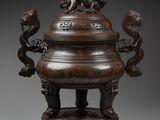 a large chinese bronze censeer with lions on top of it