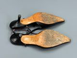 two pairs of black leather shoes on a grey surface